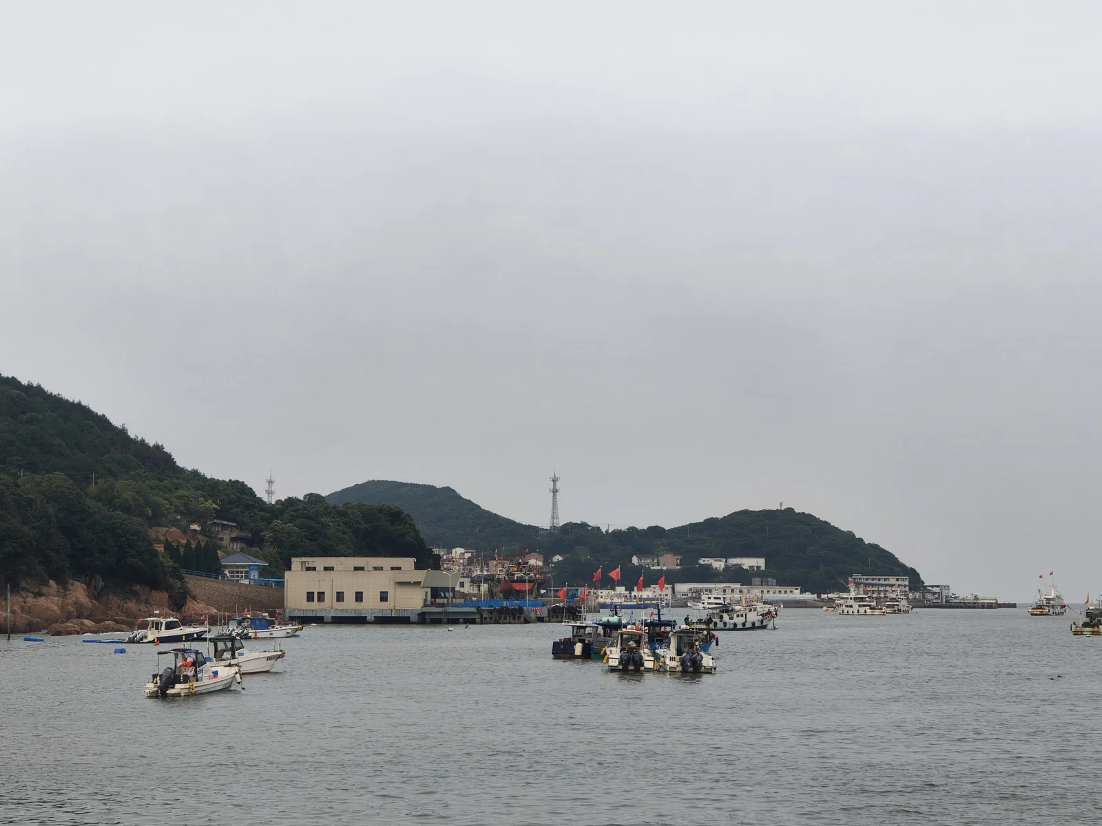 乌石塘附近的小型渔港，水面上停泊着多艘渔船，背景是郁郁葱葱的山丘