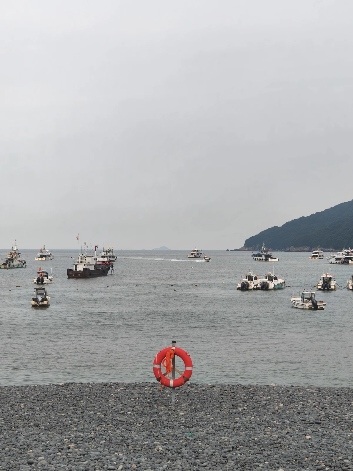 乌石塘的黑色鹅卵石海滩，海面上停泊着多艘渔船