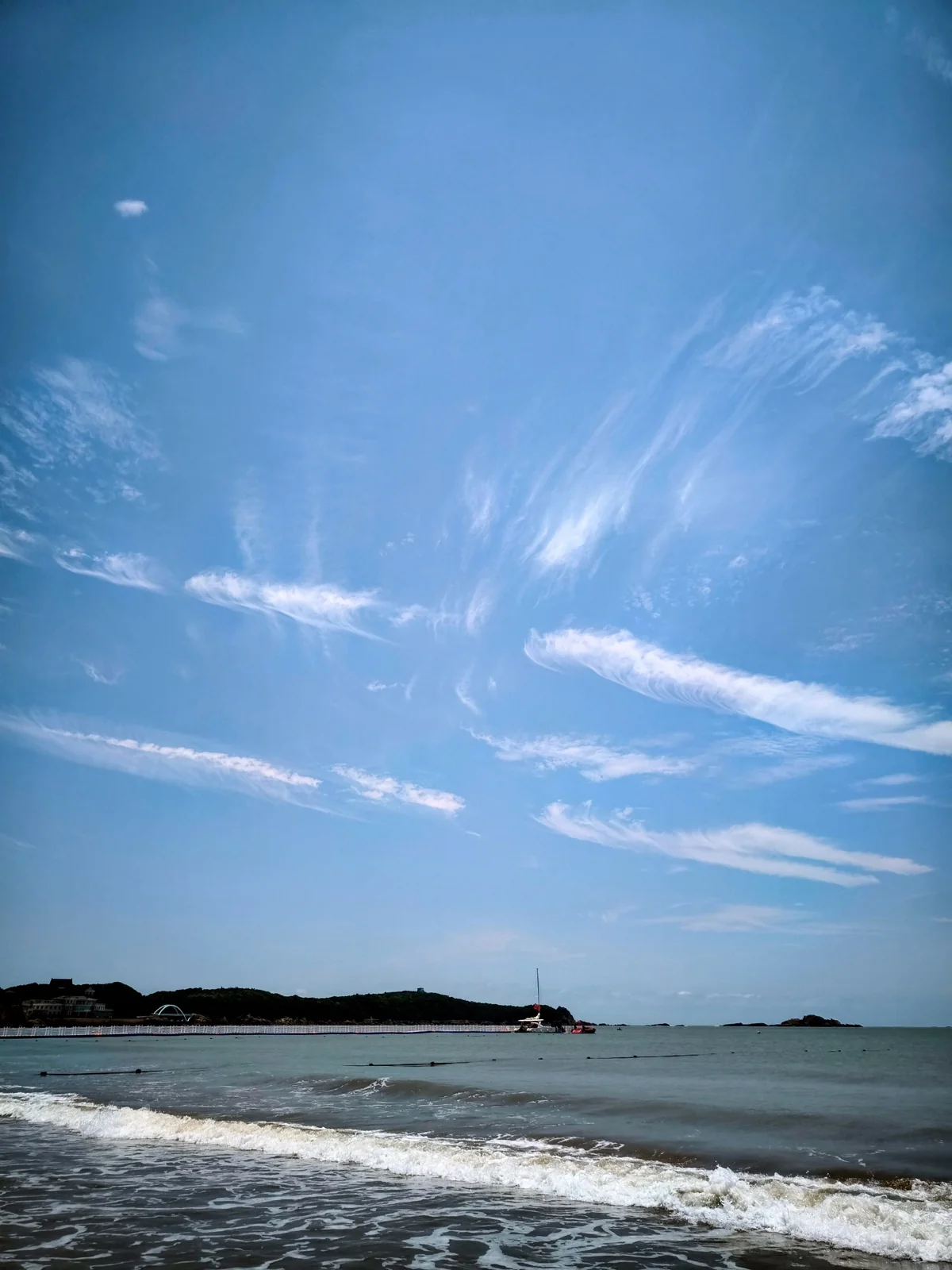 南沙海滩上空晴朗蓝天与丝状白云，海面平静