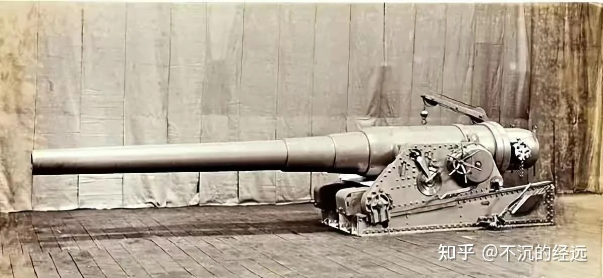 A large naval gun on a riveted carriage with a breech crane, photographed on wooden planks.