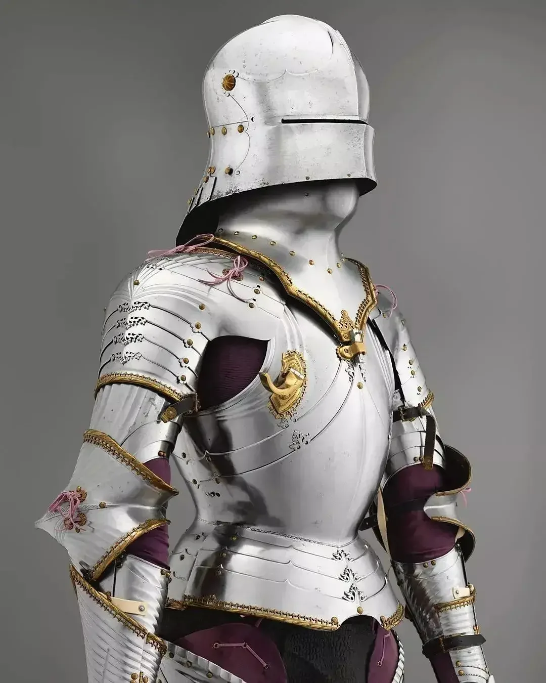 Polished European plate armor from the waist up, fluted breastplate with gilt trim and a helmet slit for the eyes.