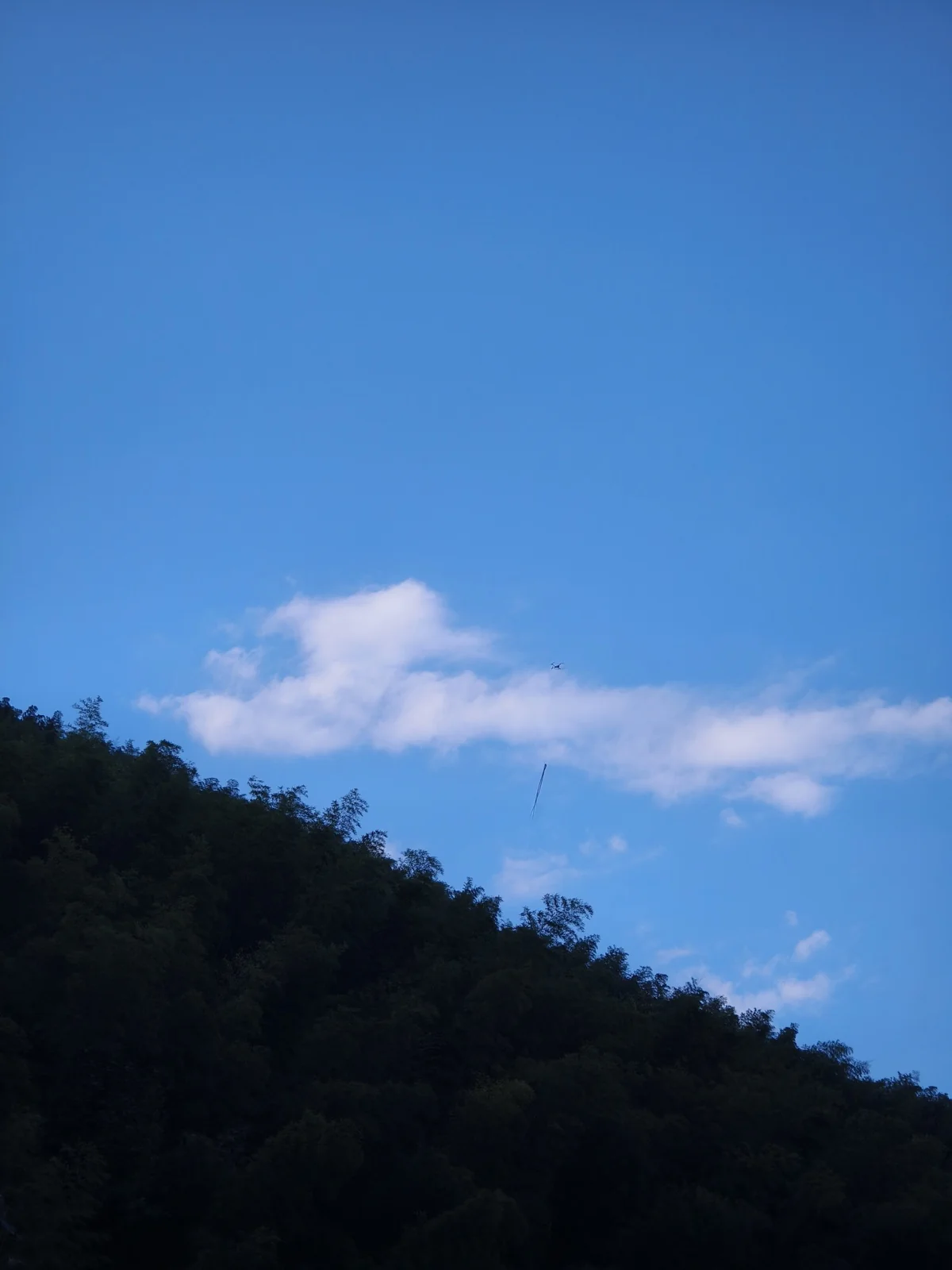 山坡上投着一大片云影，上半部是蓝天