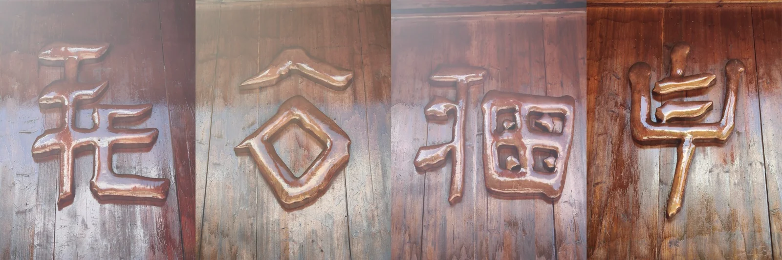 木门上凸起的四个铜色畲族装饰符号，笔画由圆角几何形拼成