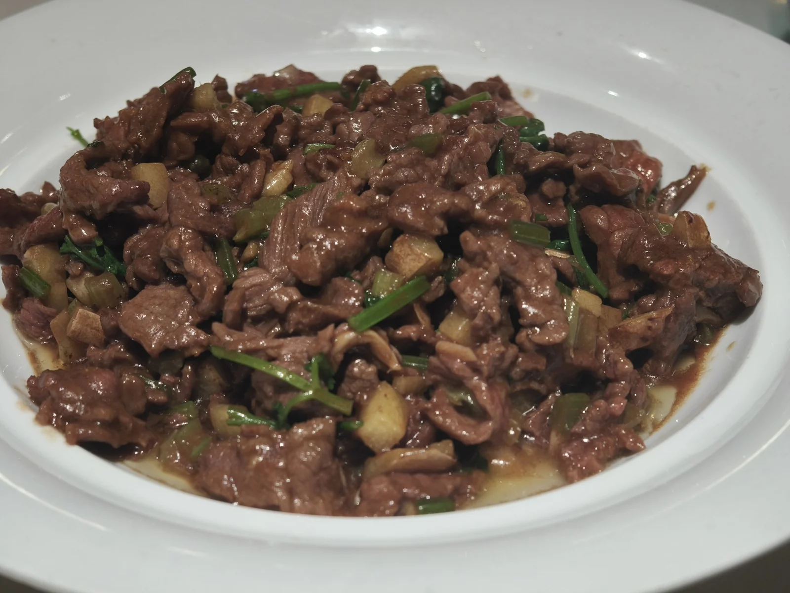 白瓷盘里是炒牛肉粒，配着青蒜和芥菜干
