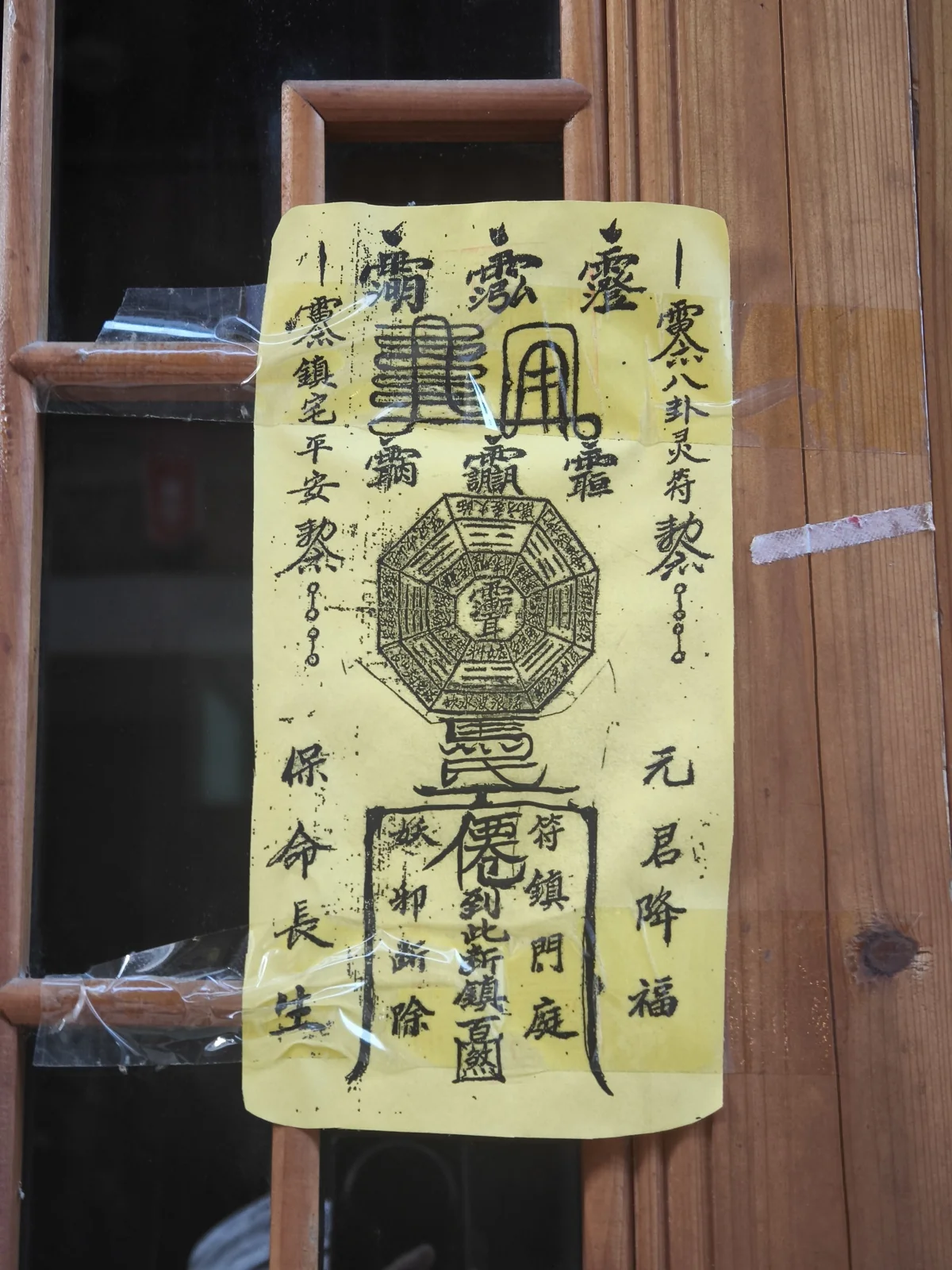 木门上贴着一张泛黄的黄纸符，符面画着八卦与朱笔文字